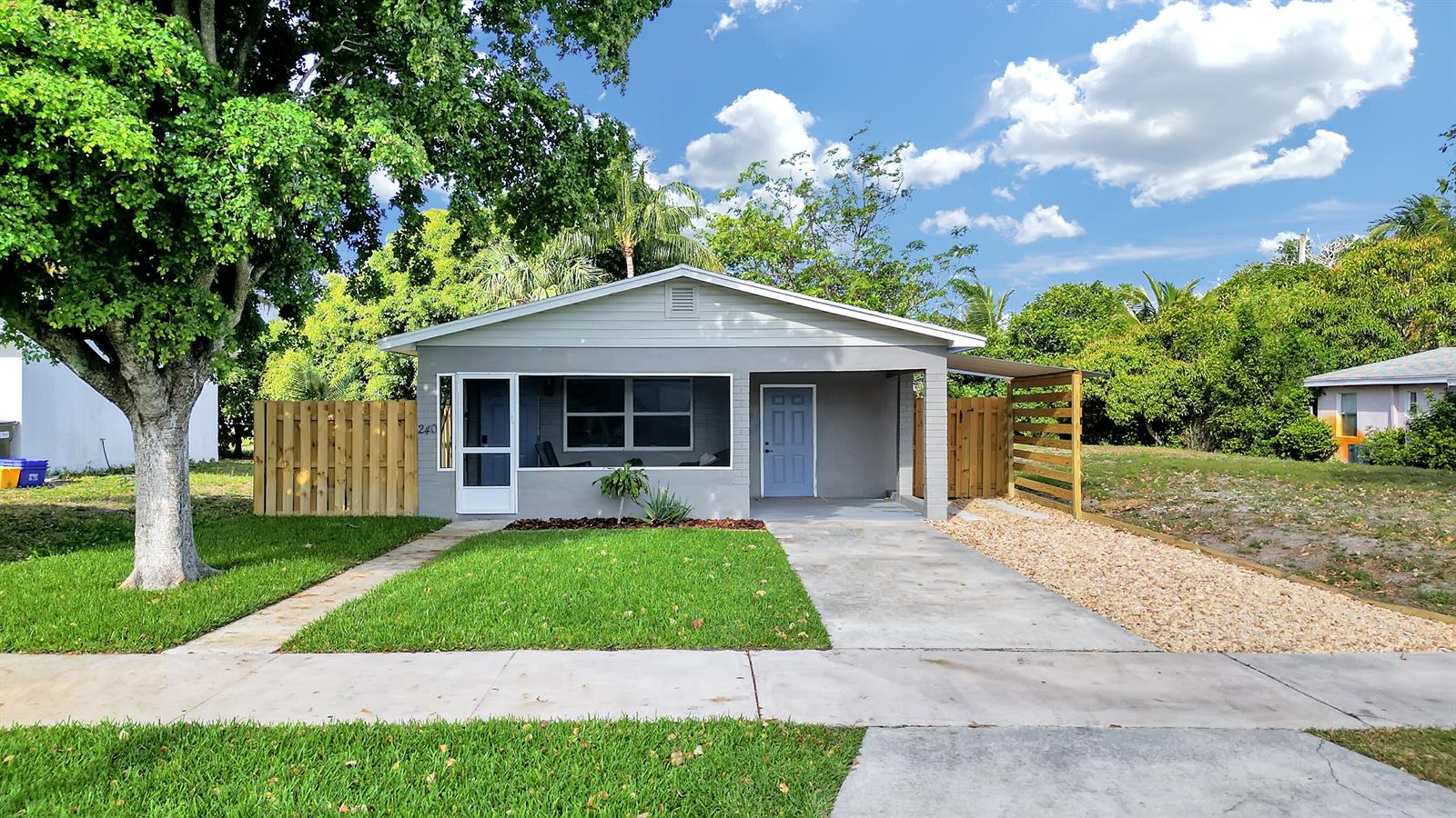 A single-story gray house with a screened porch, a blue door, and a gravel driveway — 240 NW 9th Avenue, Delray Beach FL 33444, DELRAY BEACH, FL