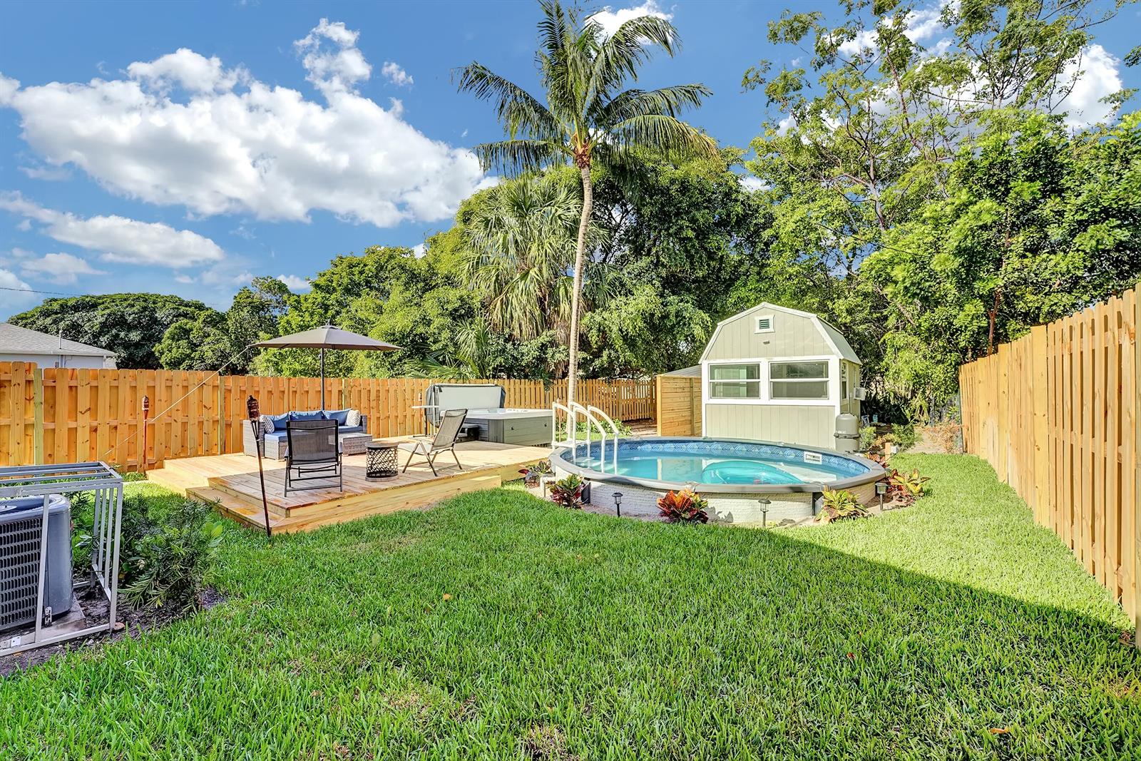 A backyard with a wooden deck, a hot tub, an above-ground pool, and a shed — 240 NW 9th Avenue, Delray Beach FL 33444, DELRAY BEACH, FL