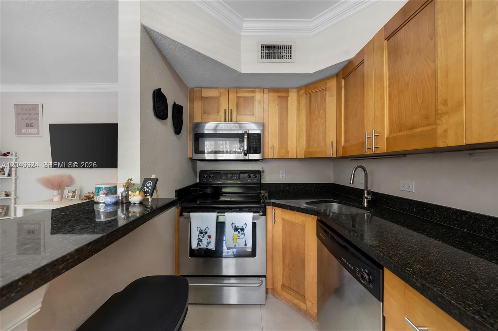 A kitchen features light wood cabinets, black granite countertops, and stainless steel appliances — FORT LAUDERDALE, FL