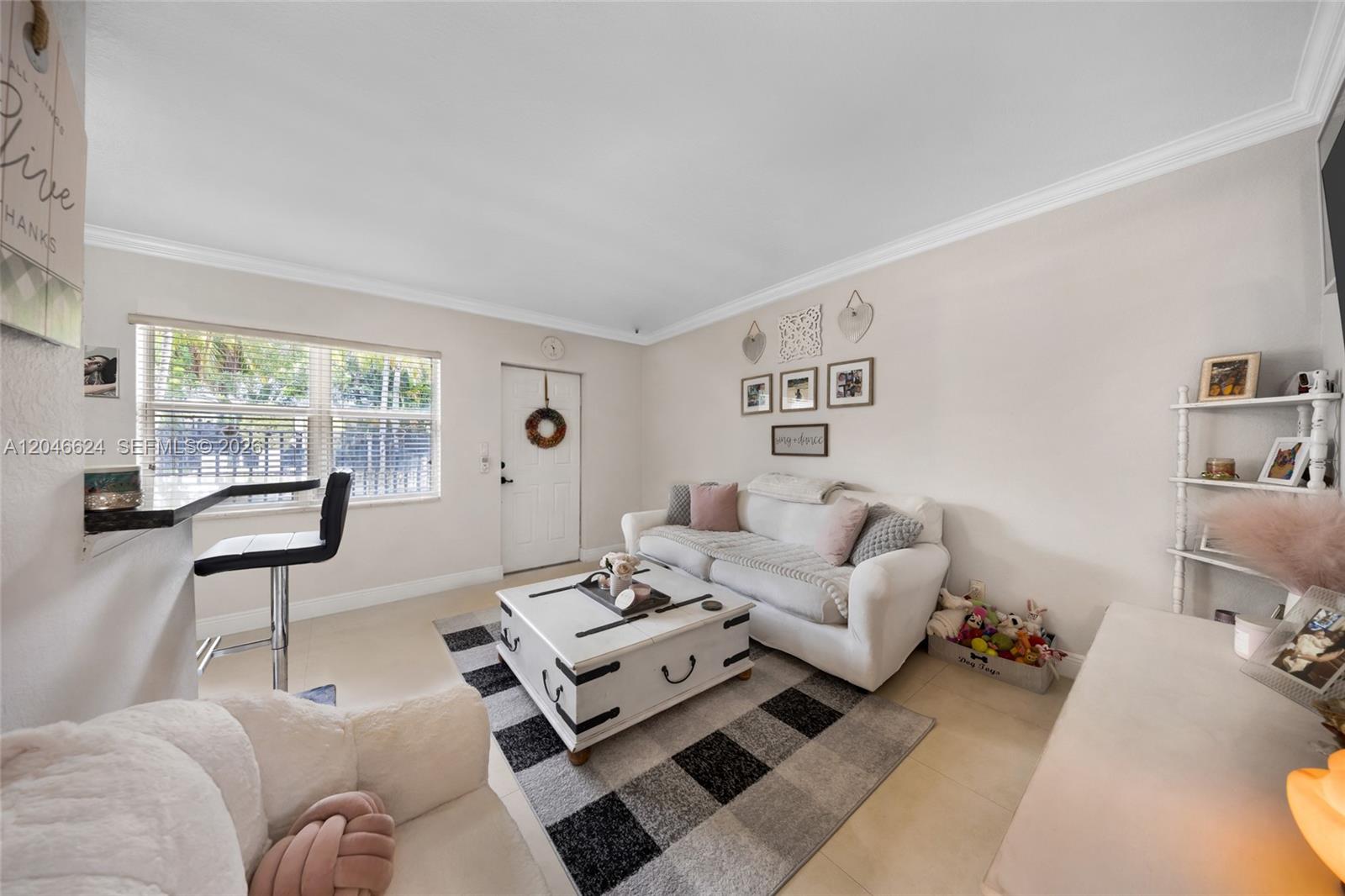 A living room features a white sofa, a trunk coffee table, and a plaid rug — FORT LAUDERDALE, FL