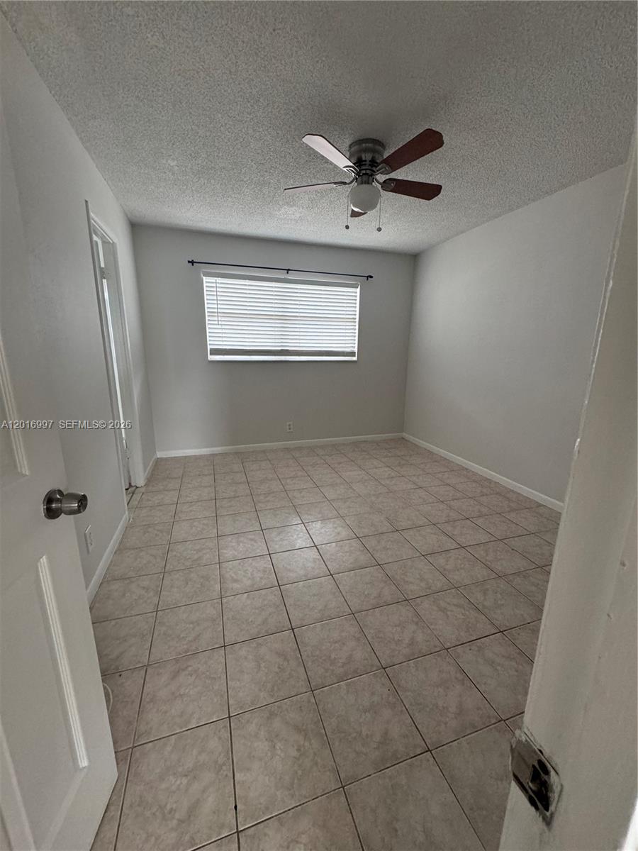 This bedroom features light gray walls, beige tile flooring, and a ceiling fan — 410 SE 2nd Ave # 21, Deerfield Beach FL 33441, DEERFIELD BEACH, FL