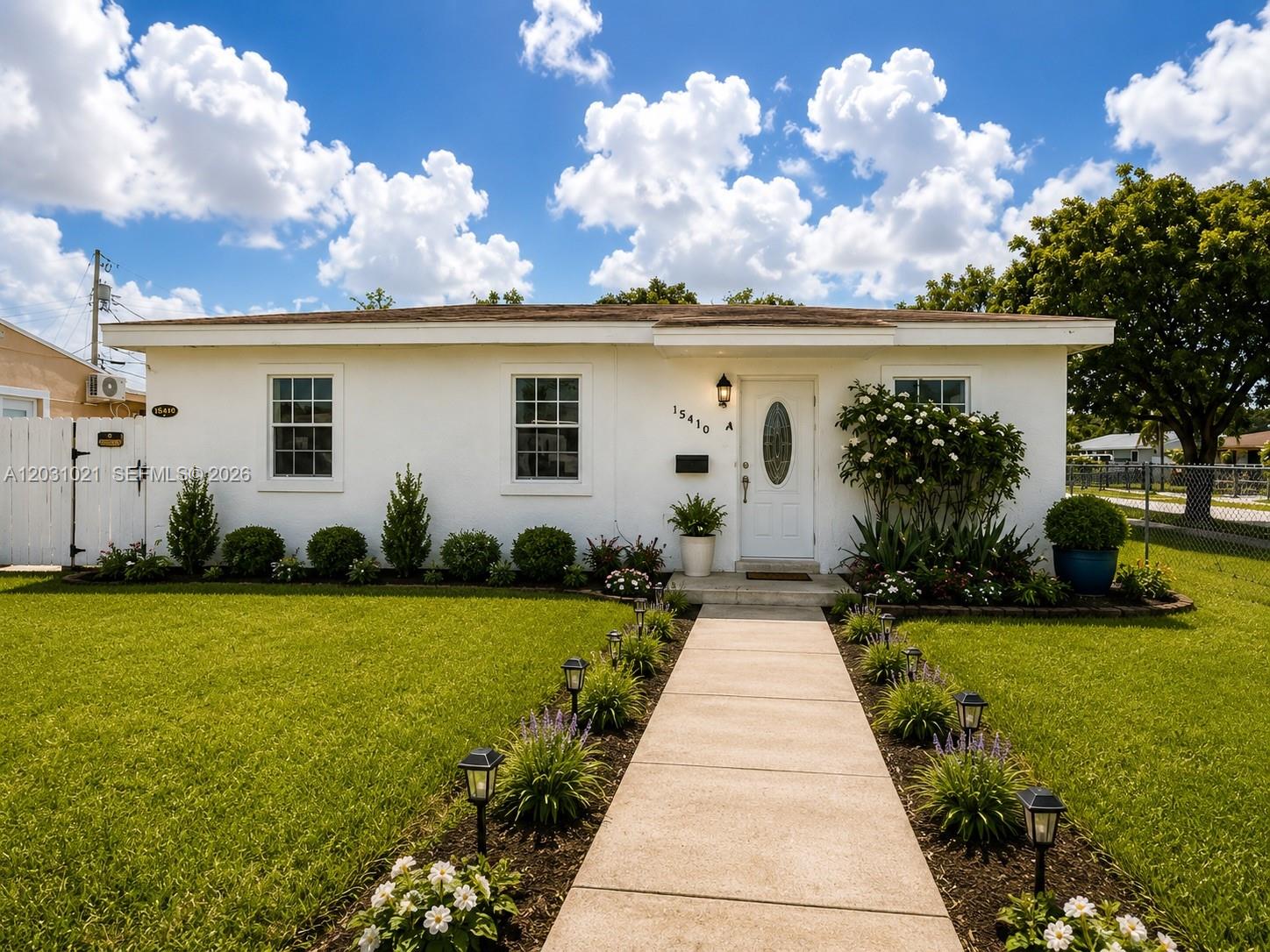 A white single-story house features a concrete walkway lined with solar lights and landscaping — 15410 NW 29th Ct # A, Miami FL 33054, MIAMI, FL