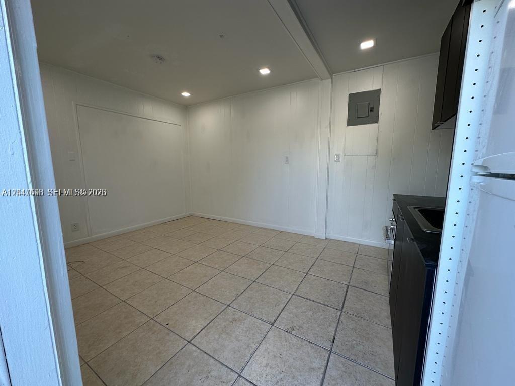 A kitchen area features white paneled walls, light tile flooring, and dark lower cabinets — 301 9th St # 1, Hallandale Beach FL 33009, HALLANDALE BEACH, FL