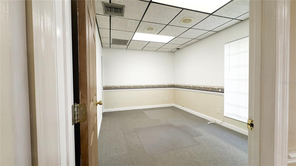 An empty office room features gray carpeting, white walls with chair rail molding, and drop ceilings — 3612 5TH AVENUE N, ST PETERSBURG, FL