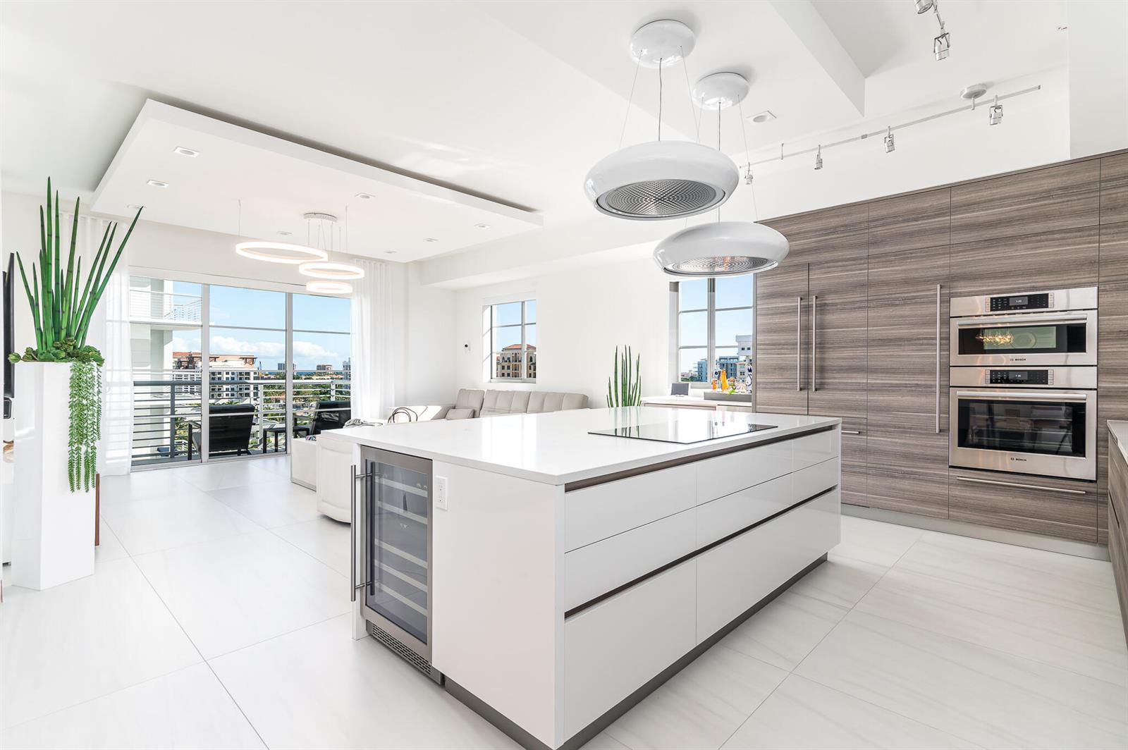 A modern kitchen features a white island, wood-toned cabinetry, and a balcony with outdoor seating — 155 E Boca Raton Road # 820, Boca Raton FL 33432, BOCA RATON, FL