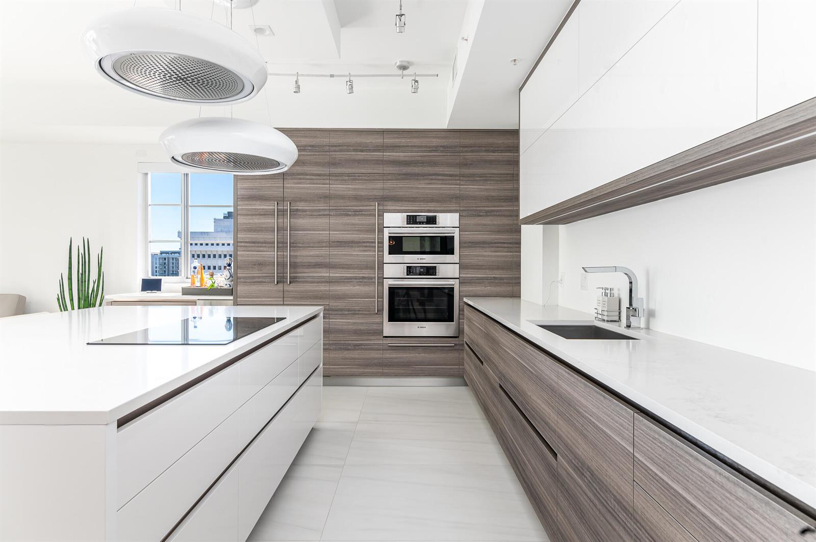 A modern kitchen features white countertops, wood-grain cabinetry, stainless steel appliances, and two pendant lights — 155 E Boca Raton Road # 820, Boca Raton FL 33432, BOCA RATON, FL