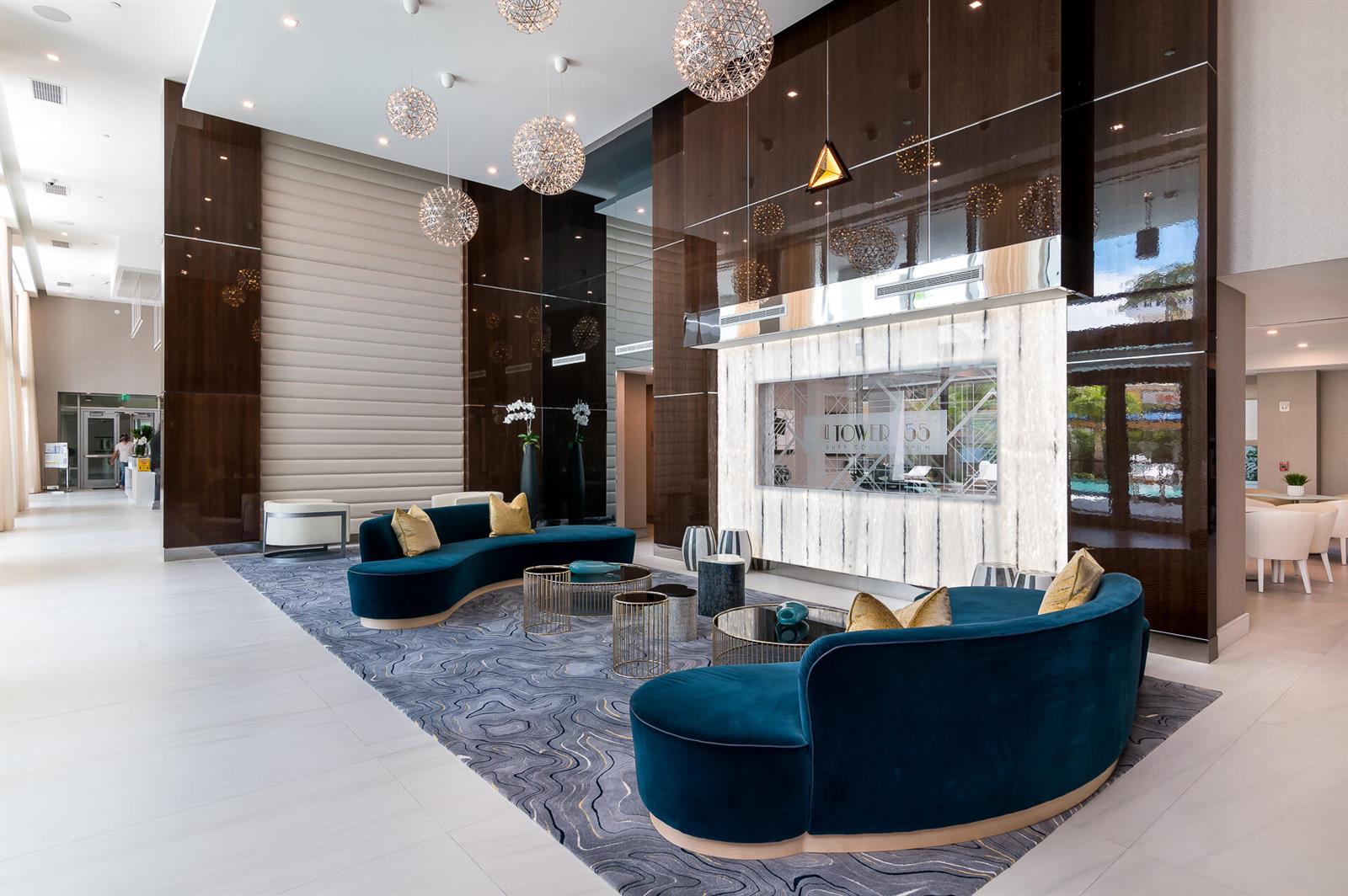 A modern lobby features two curved blue velvet sofas, a patterned rug, and spherical pendant lights — 155 E Boca Raton Road # 820, Boca Raton FL 33432, BOCA RATON, FL