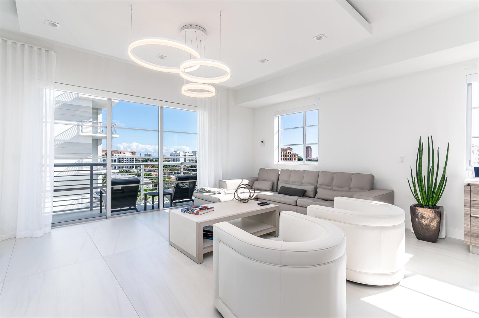 A bright living room features white tile floors, a gray sectional, and a modern ring chandelier — 155 E Boca Raton Road # 820, Boca Raton FL 33432, BOCA RATON, FL