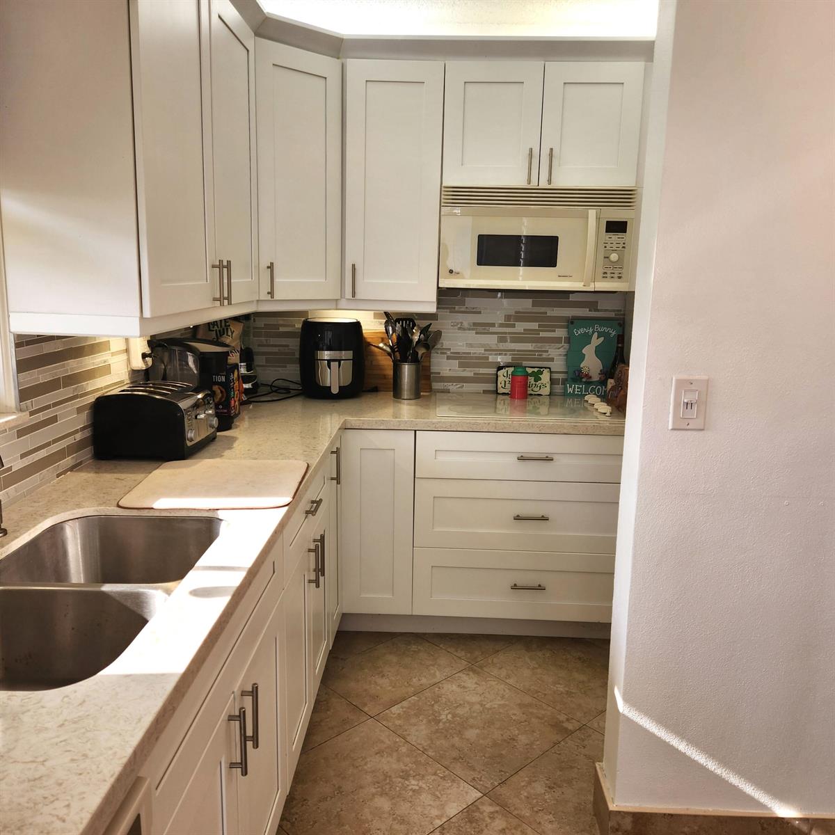 A kitchen with white cabinets, stainless steel appliances, a tiled backsplash, and light countertops — 745 SE 19th Avenue # 112, Deerfield Beach FL 33441, DEERFIELD BEACH, FL
