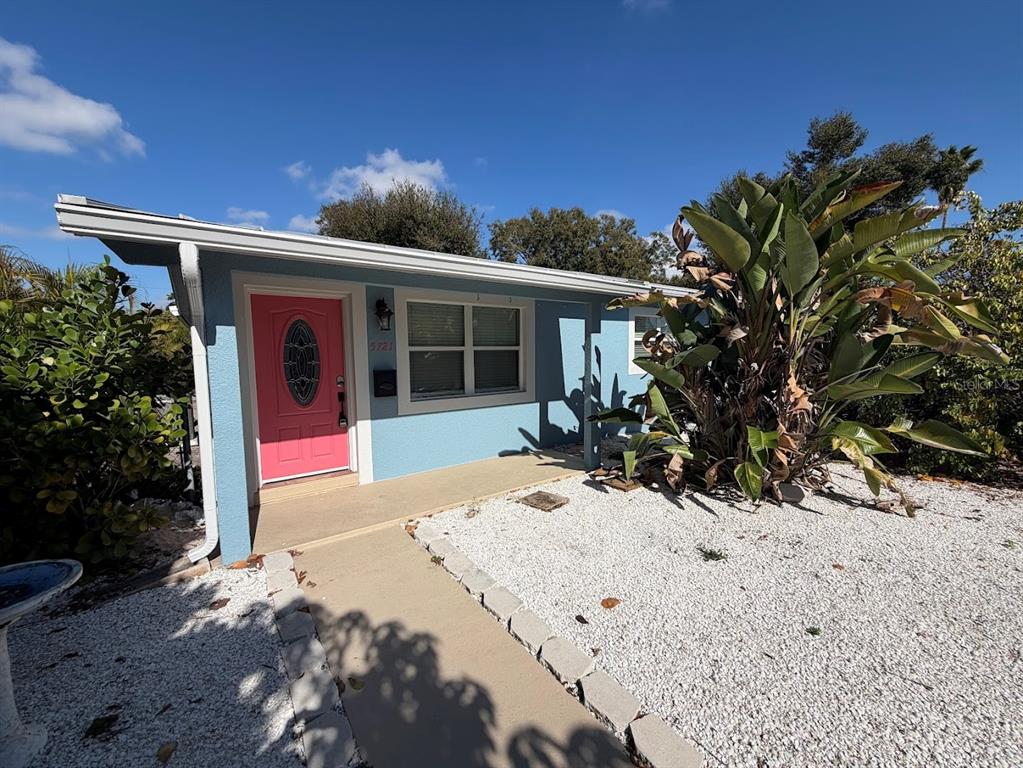 A light blue house with a bright pink front door and a white gravel yard — 5721 10TH AVENUE N, ST PETERSBURG, FL