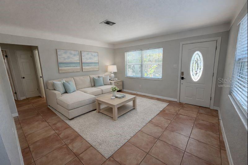 A living room with tile floors, a sectional sofa, a coffee table, and a front door — 5721 10TH AVENUE N, ST PETERSBURG, FL