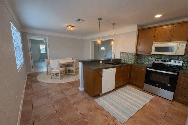 A kitchen with wood cabinets and a dining area with a round table and chairs — 5721 10TH AVENUE N, ST PETERSBURG, FL