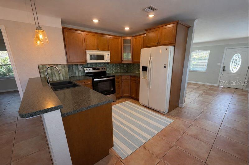 A kitchen with wood cabinets, dark countertops, a white refrigerator, and tiled flooring — 5721 10TH AVENUE N, ST PETERSBURG, FL