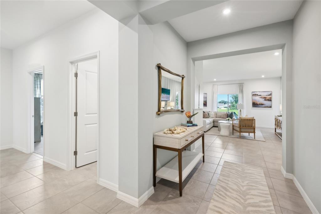 A hallway with tile flooring leads to a living room featuring a console table — 12912 CARA COURT, GRAND ISLAND, FL