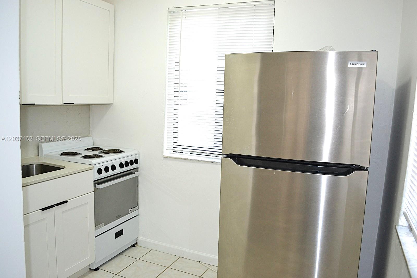 A small kitchen features white cabinets, a white electric stove, and a stainless steel refrigerator — 1035 SW 4th St # 4, Miami FL 33130, MIAMI, FL