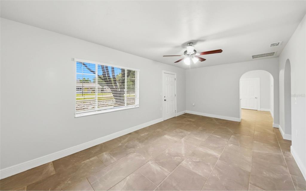 A room with light gray walls, tile flooring, a ceiling fan, and a large window — 1715 SUNSET DRIVE, LONGWOOD, FL