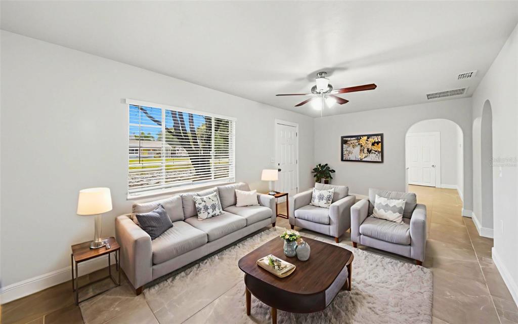A living room features a grey sofa, two armchairs, a coffee table, and tile flooring — 1715 SUNSET DRIVE, LONGWOOD, FL