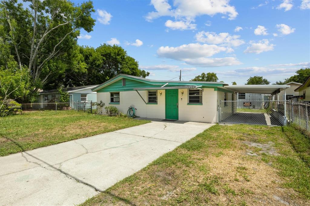 A single-story house with a green door, teal trim, and a concrete driveway — 1307 MAYFLOWER DRIVE, LAKELAND, FL