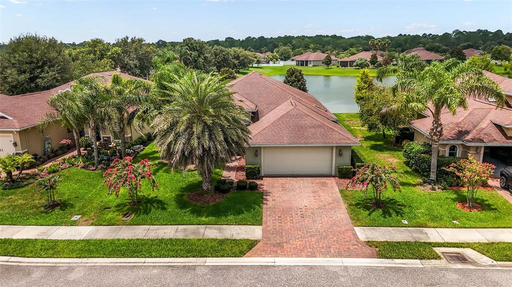 An aerial view of a suburban house with a brick driveway and a backyard pond — 64 ARENA LAKE DRIVE, PALM COAST, FL