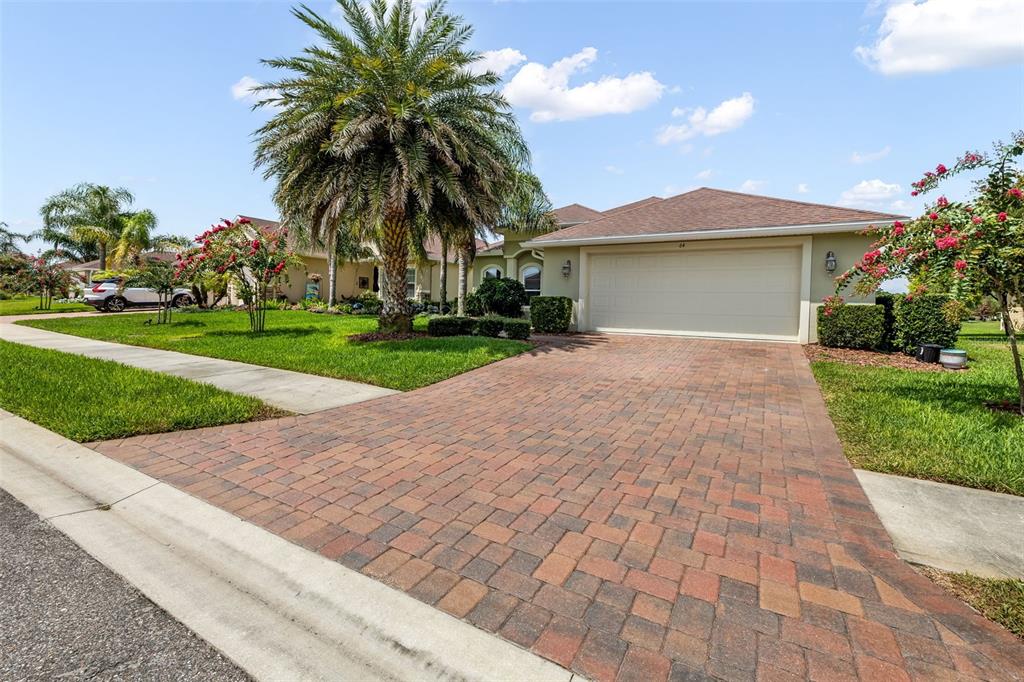 A single-story house with a paved driveway, a palm tree, and a two-car garage — 64 ARENA LAKE DRIVE, PALM COAST, FL