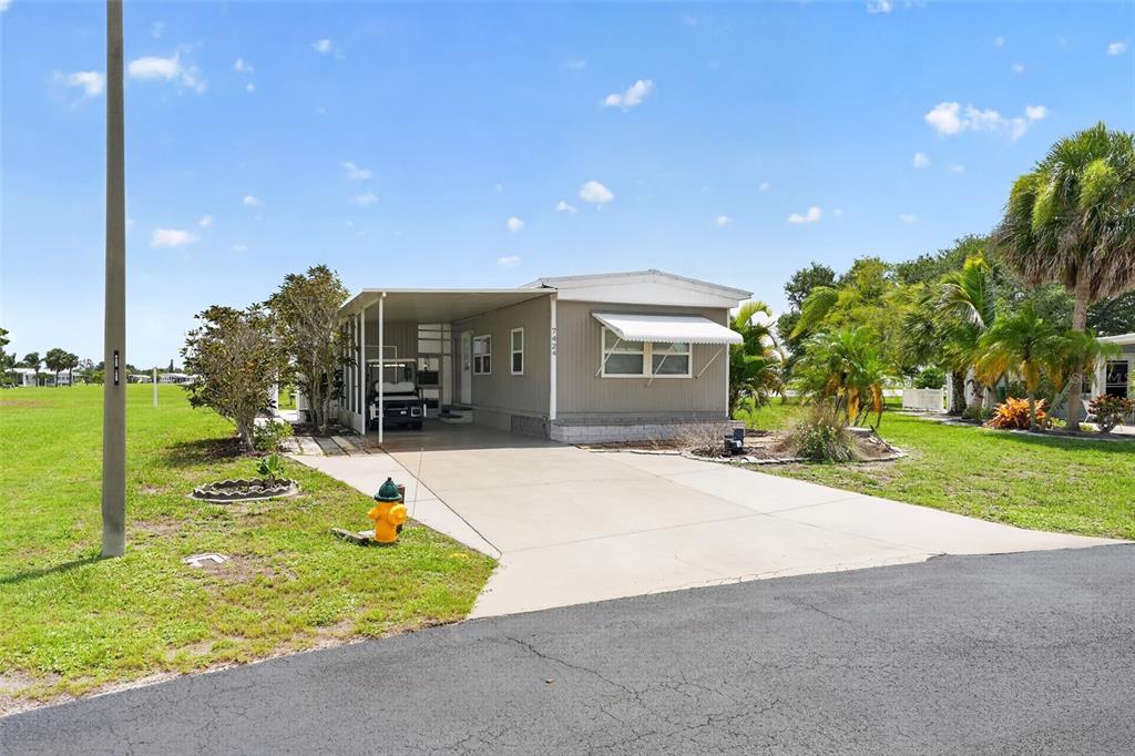A single-story mobile home with a carport, concrete driveway, and a fire hydrant in front — 7424 WIDNESS LANE, PORT CHARLOTTE, FL