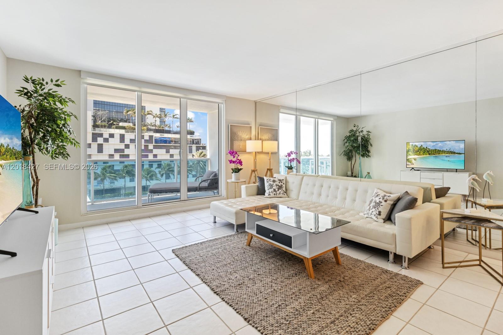 A living room features white tile floors, a sectional sofa, a coffee table, and mirrors — 2301 Collins Ave # 404, Miami Beach FL 33139, MIAMI BEACH, FL