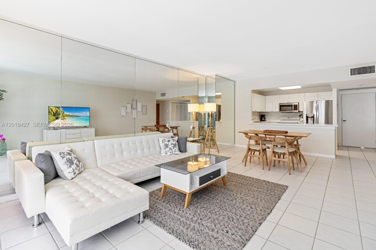 A living room with a white sectional sofa, glass coffee table, and an adjacent dining area — 2301 Collins Ave # 404, Miami Beach FL 33139, MIAMI BEACH, FL
