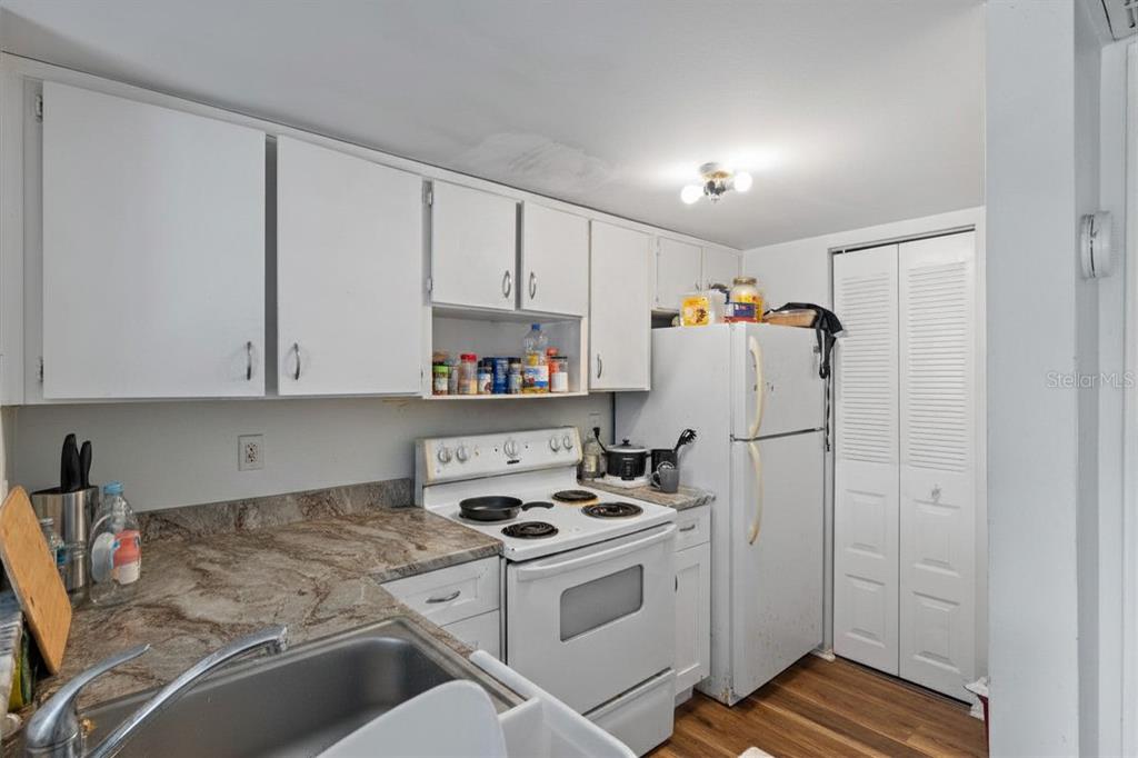 A kitchen features white cabinets, a white stove, a white refrigerator, and granite countertops — 3840 N LAKE DRIVE UNIT 125, TAMPA, FL