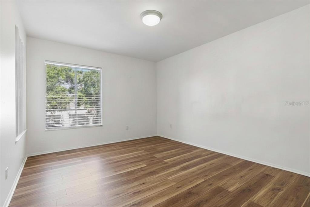 An empty room features white walls, a single window, and wood-look laminate flooring — 3840 N LAKE DRIVE UNIT 125, TAMPA, FL