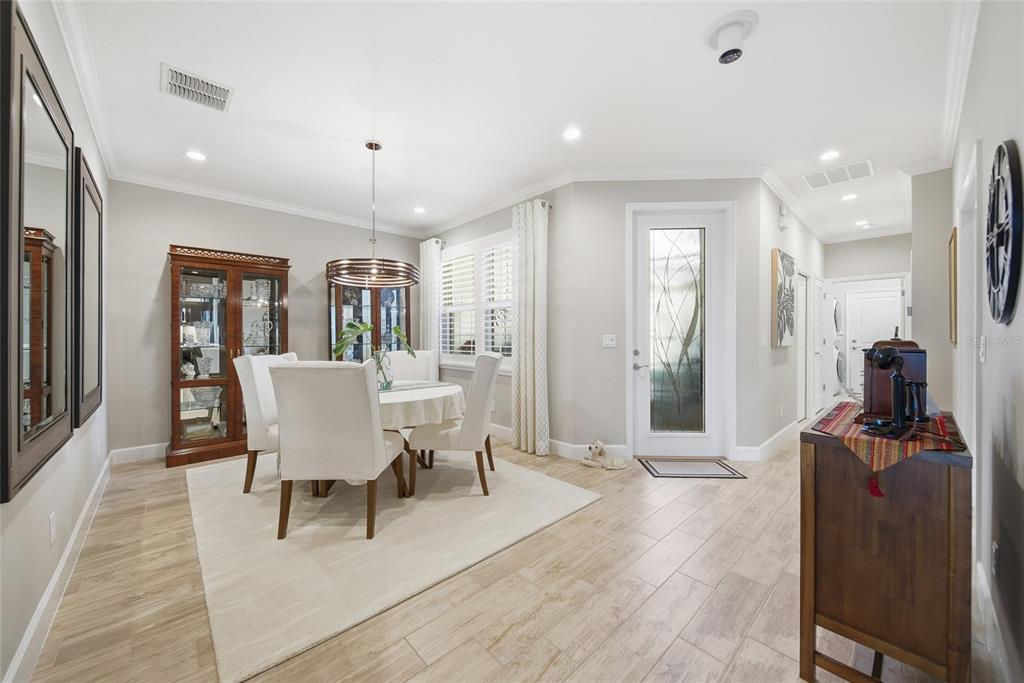 A dining room with a round table, white chairs, a china cabinet, and wood-look flooring — 4717 AVILA LAKES DRIVE, WIMAUMA, FL