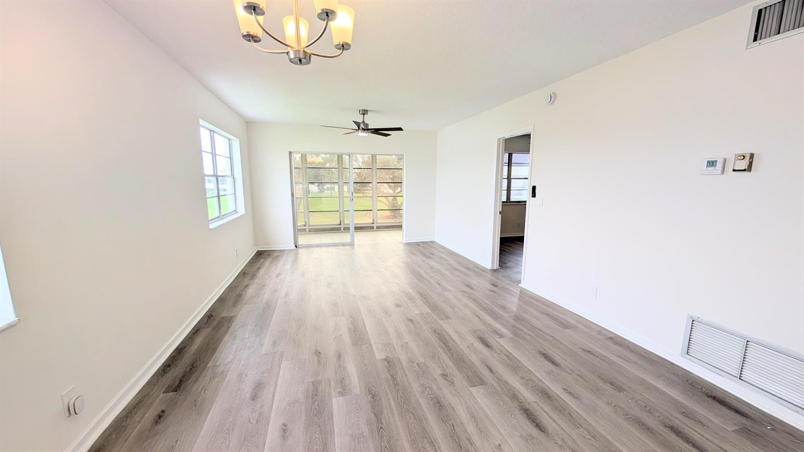 An empty room features light wood-look flooring, white walls, a ceiling fan, and sliding doors — 2800 W Golf Boulevard # 219, Pompano Beach FL 33064, POMPANO BEACH, FL