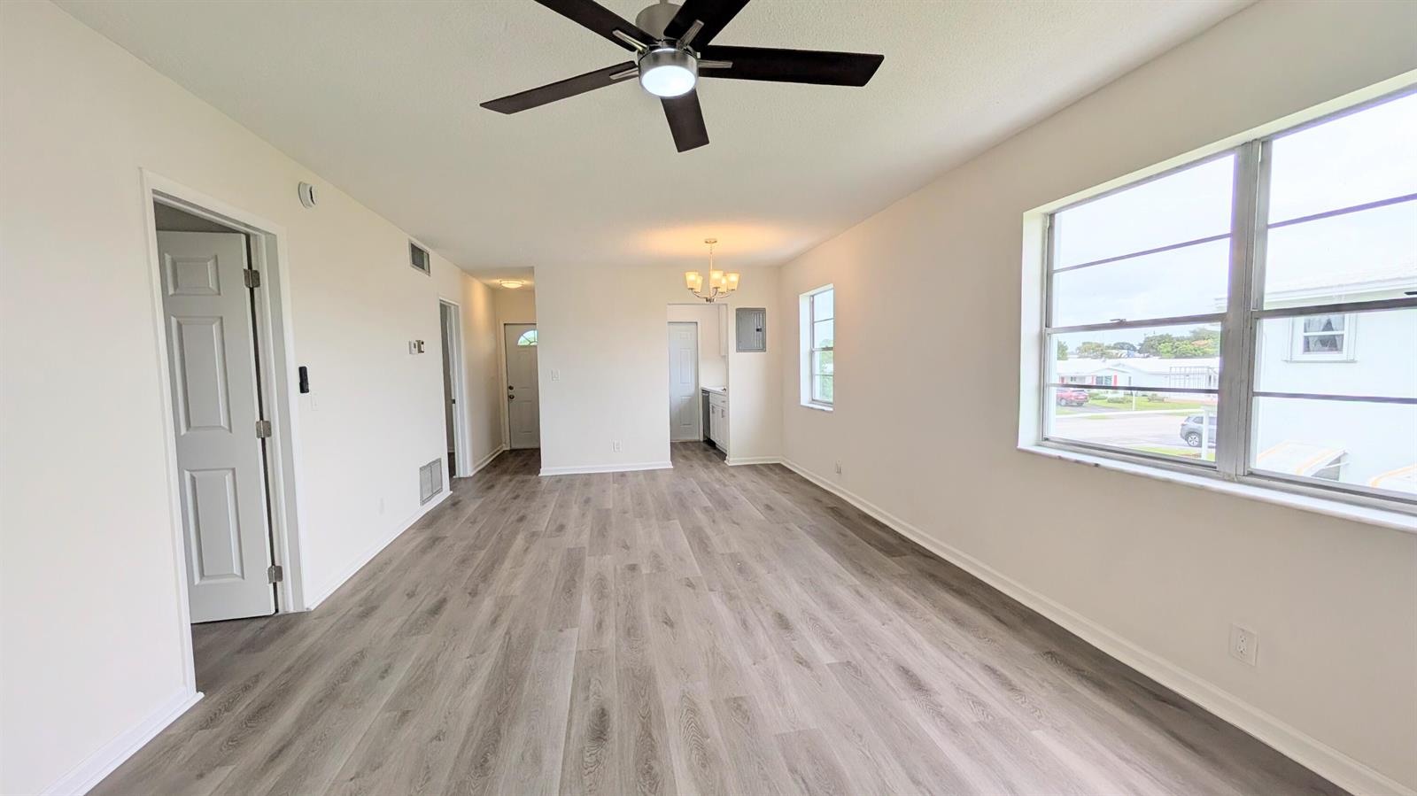 An empty living room features light wood-look flooring, white walls, and a ceiling fan — 2800 W Golf Boulevard # 219, Pompano Beach FL 33064, POMPANO BEACH, FL