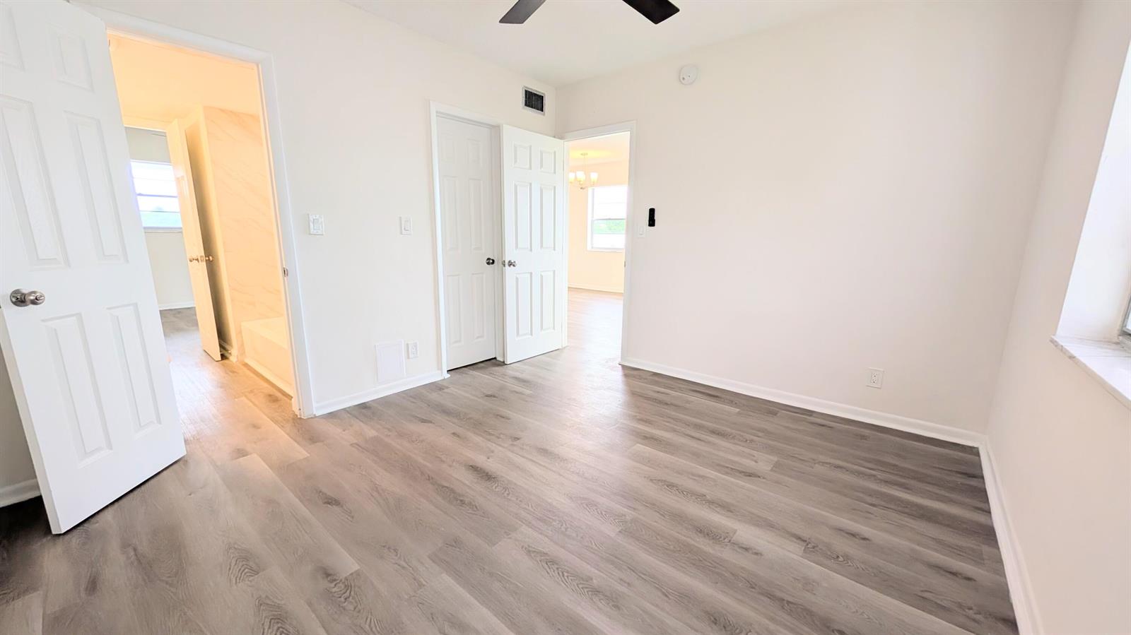 An empty bedroom features light wood-look flooring, white walls, and two open doorways — 2800 W Golf Boulevard # 219, Pompano Beach FL 33064, POMPANO BEACH, FL