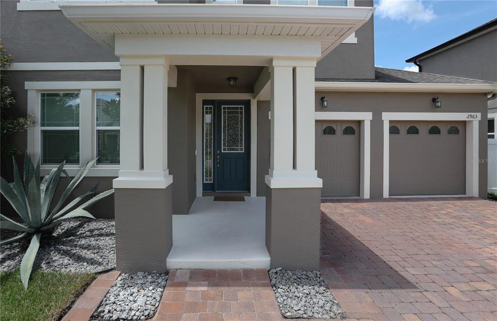 A front exterior view of a house with a covered entryway and a two-car garage — 2963 SERA BELLA WAY, KISSIMMEE, FL