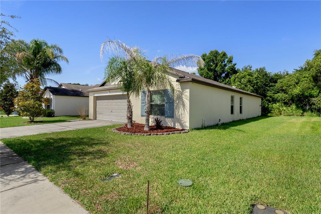 A single-story house with a beige exterior, a two-car garage, and a palm tree out front — 2987 MOULDEN HOLLOW DRIVE, ZEPHYRHILLS, FL