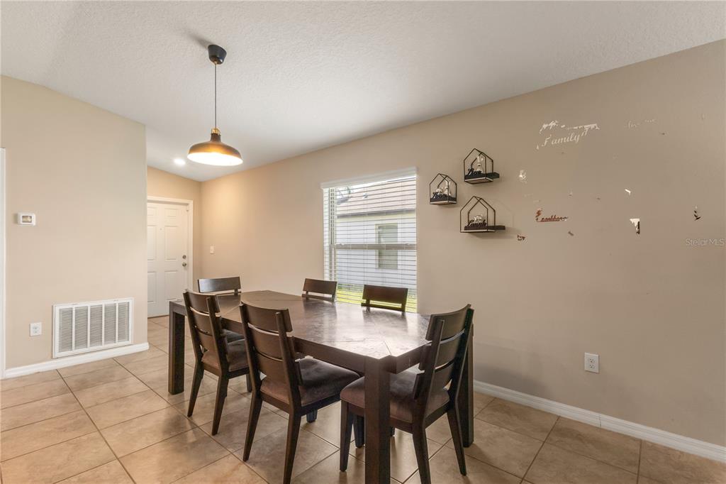 A dining room features a dark wood table, six chairs, tile flooring, and wall decor — 2987 MOULDEN HOLLOW DRIVE, ZEPHYRHILLS, FL