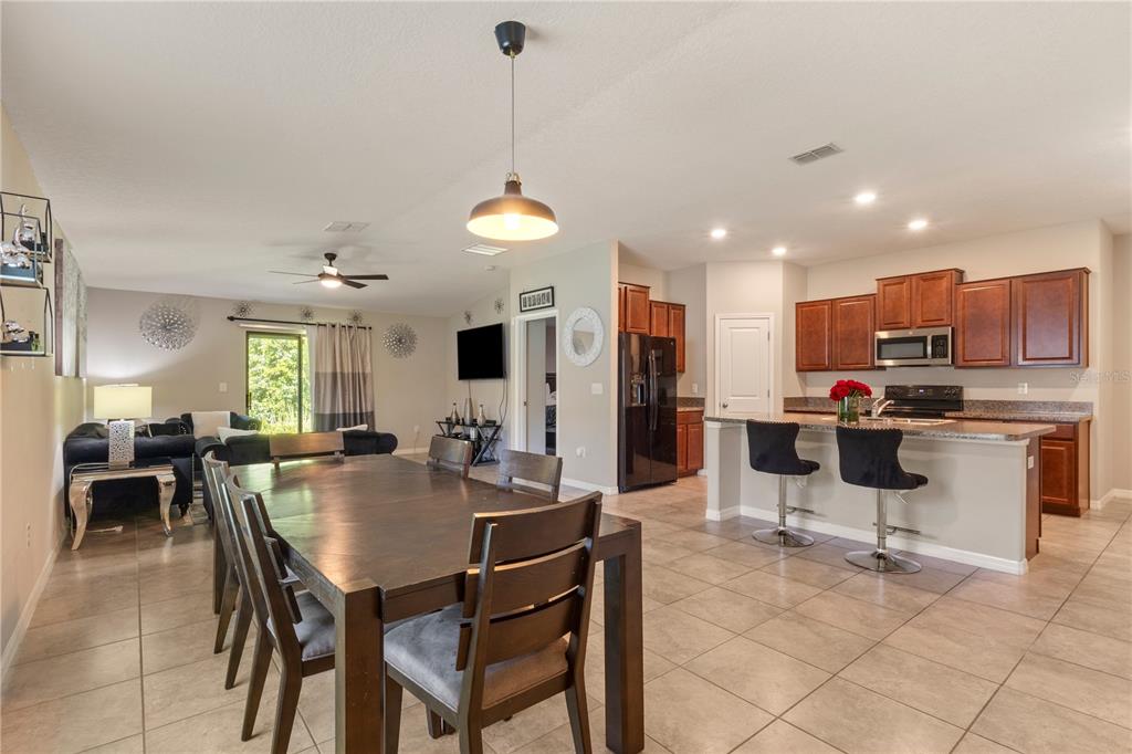 An open-concept kitchen and dining area with tile flooring and dark wood cabinetry — 2987 MOULDEN HOLLOW DRIVE, ZEPHYRHILLS, FL