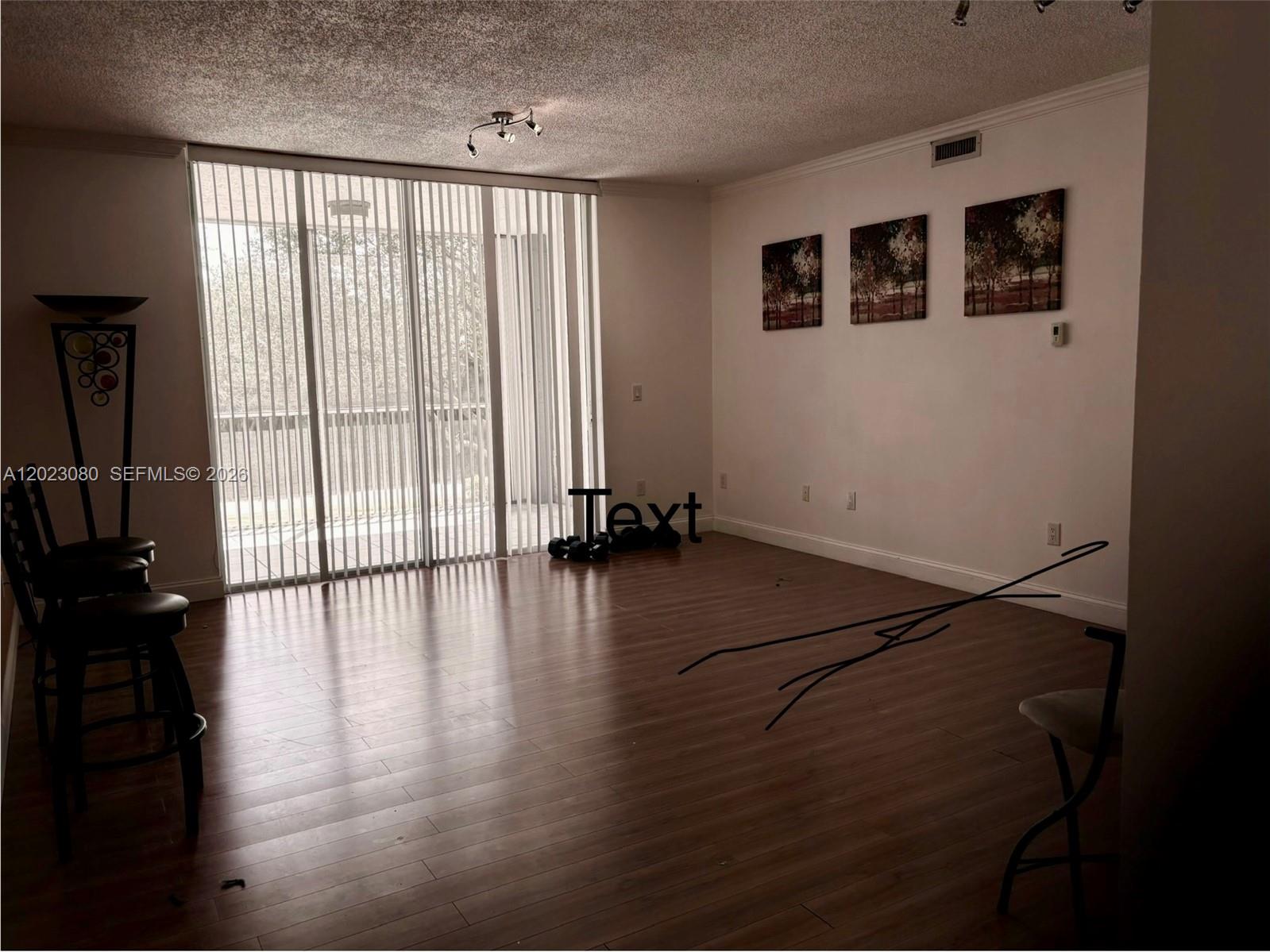 A living area with wood-look flooring, a popcorn ceiling, and a sliding glass door — DORAL, FL
