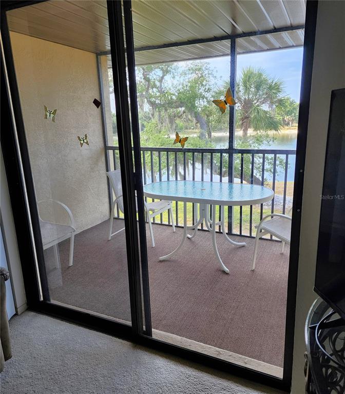 A screened-in balcony features a table and chairs overlooking a lake and trees — 4056 OAKVIEW DRIVE UNIT E10, PORT CHARLOTTE, FL