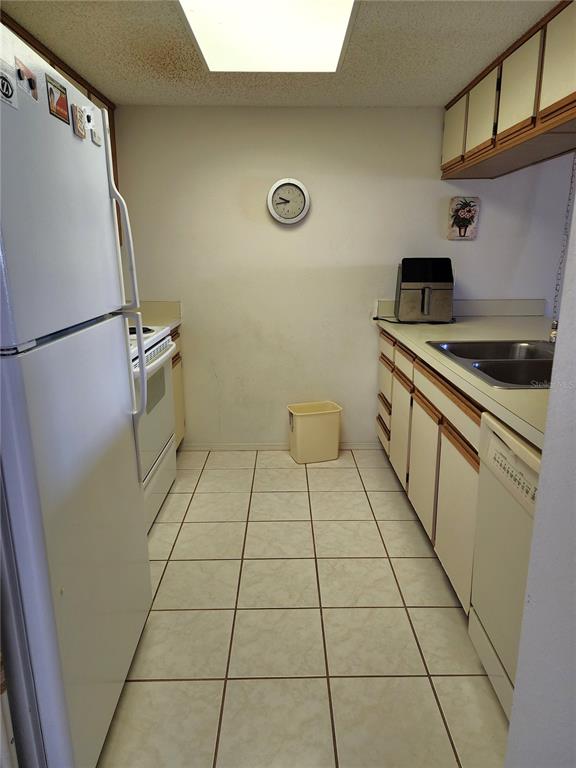 A galley kitchen features white appliances, light-colored cabinets, and tiled flooring — 4056 OAKVIEW DRIVE UNIT E10, PORT CHARLOTTE, FL
