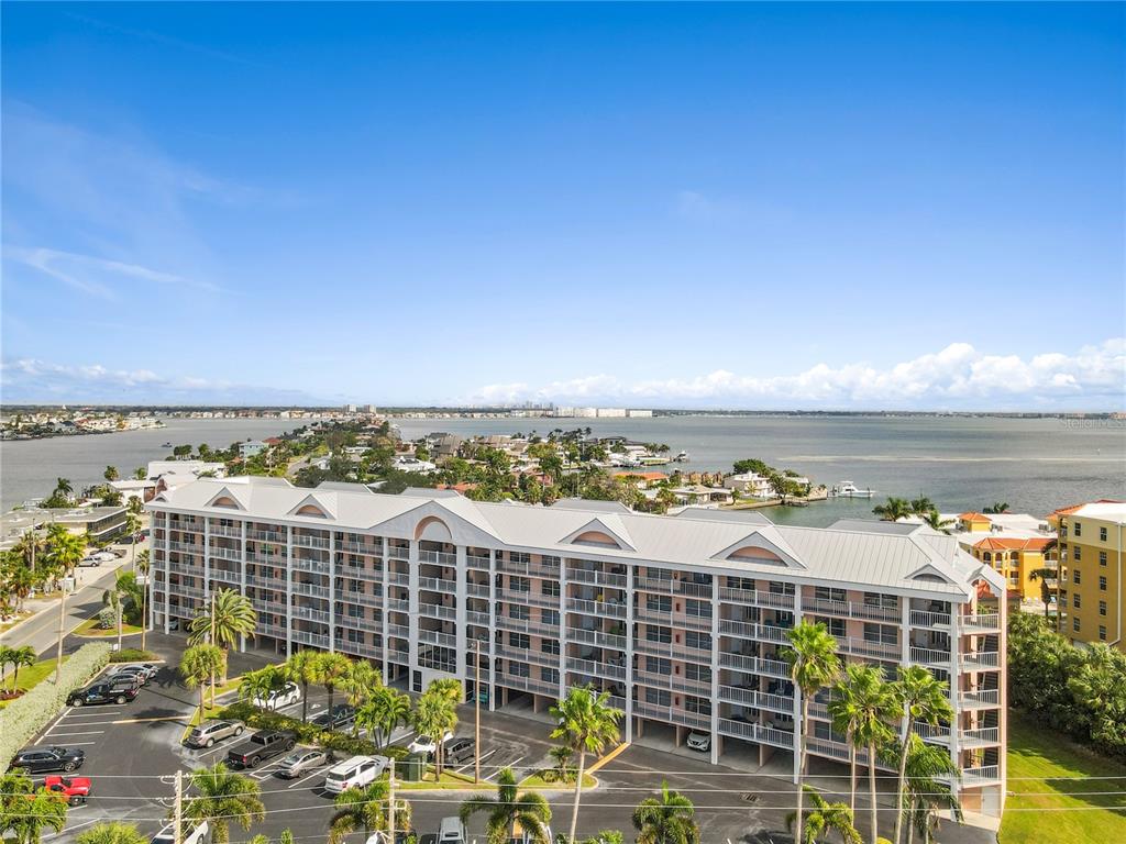 An aerial view of a multi-story apartment building situated near a large body of water — 5445 GULF BOULEVARD UNIT PH1, ST PETE BEACH, FL
