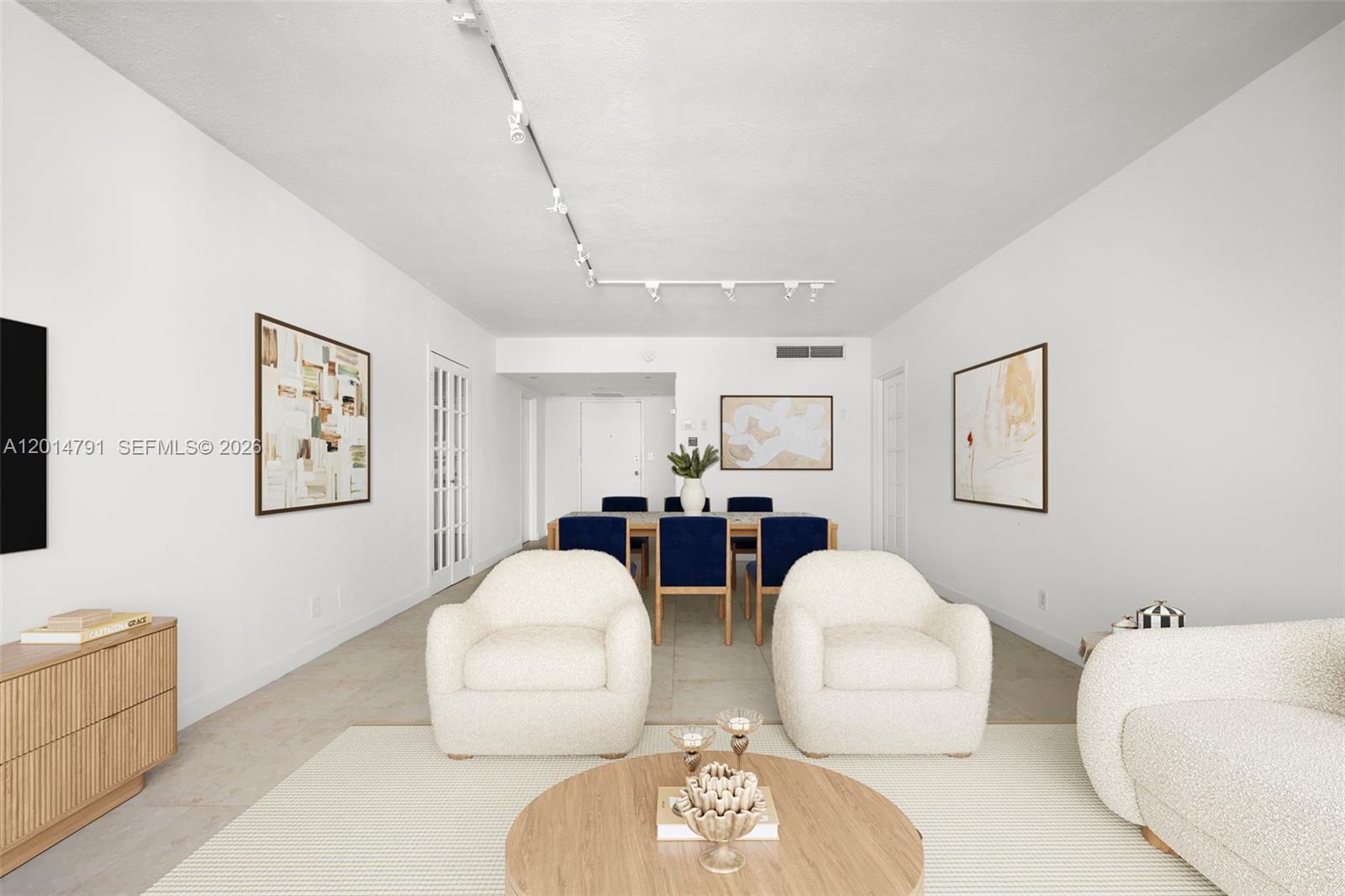 A living and dining area features white walls, cream furniture, and a wooden dining table — 900 Bay Dr # 1005, Miami Beach FL 33141, MIAMI BEACH, FL