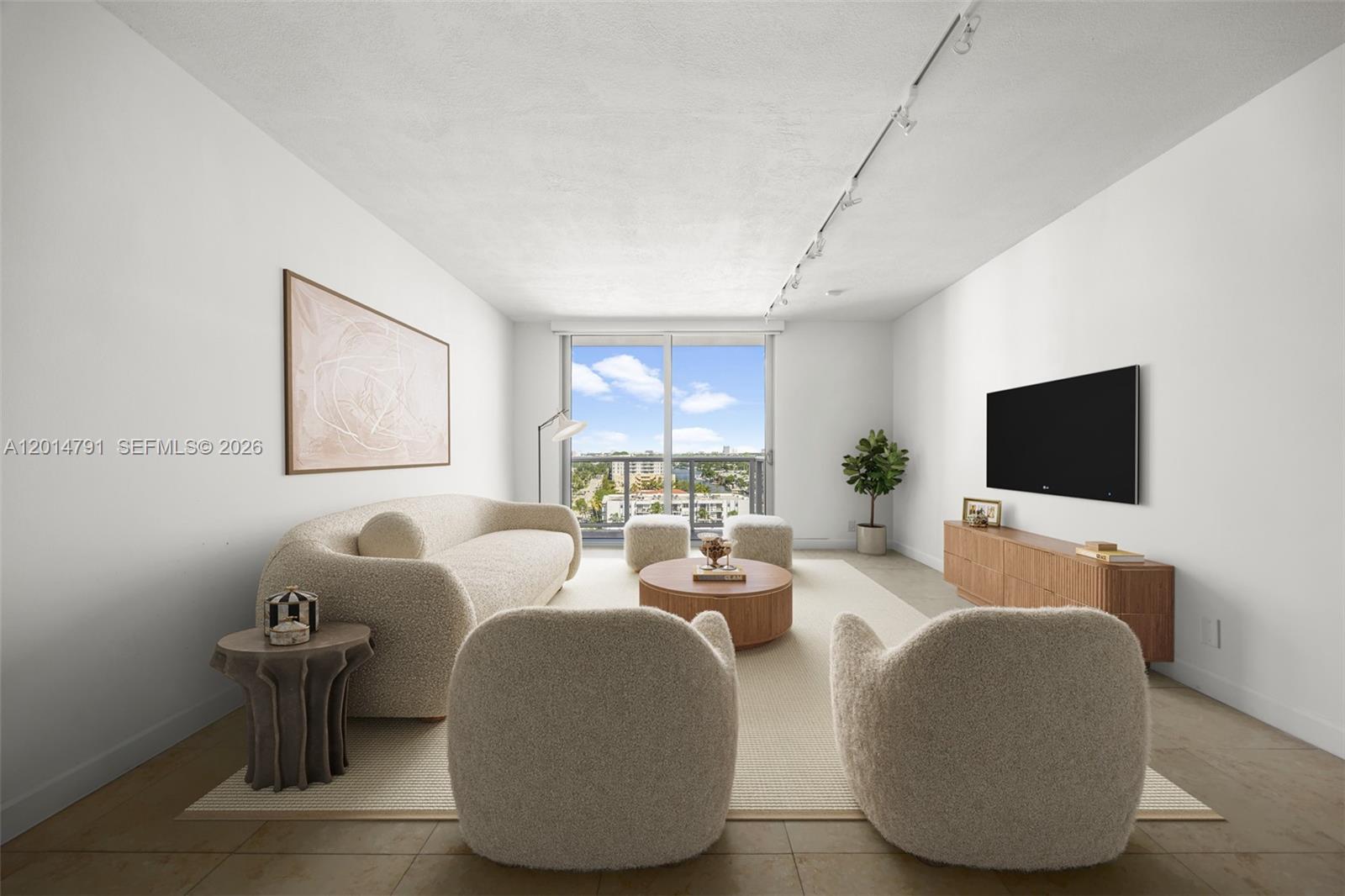 A modern living room features a curved sofa, two armchairs, and a view of buildings — 900 Bay Dr # 1005, Miami Beach FL 33141, MIAMI BEACH, FL