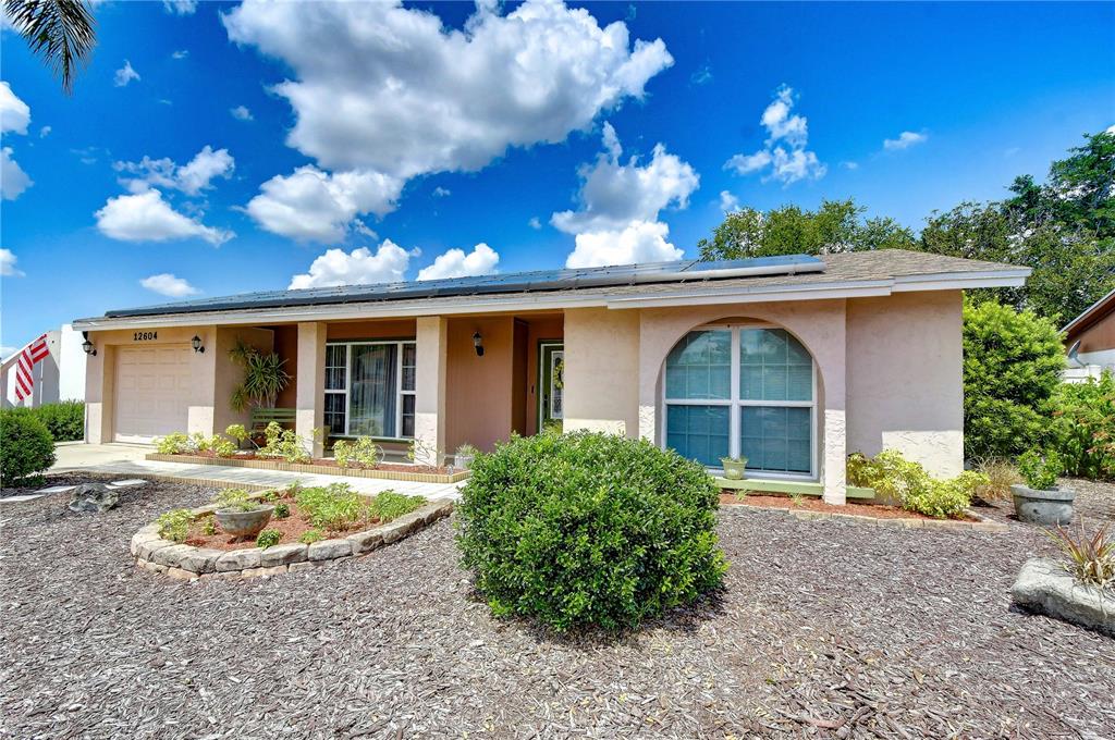 A single-story house with a tan stucco exterior, a front porch, and a gravel yard — 12604 TRUCIOUS PLACE, TAMPA, FL