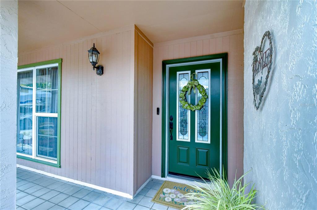 A green front door with a wreath and a welcome mat on a covered porch — 12604 TRUCIOUS PLACE, TAMPA, FL