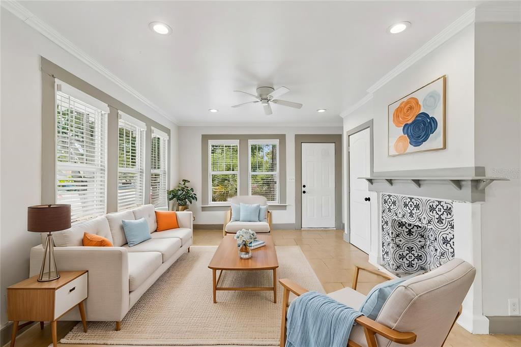 A living room features a patterned tile fireplace, light-colored sofa, and wood-framed armchairs — 4105 18TH AVENUE S, ST PETERSBURG, FL