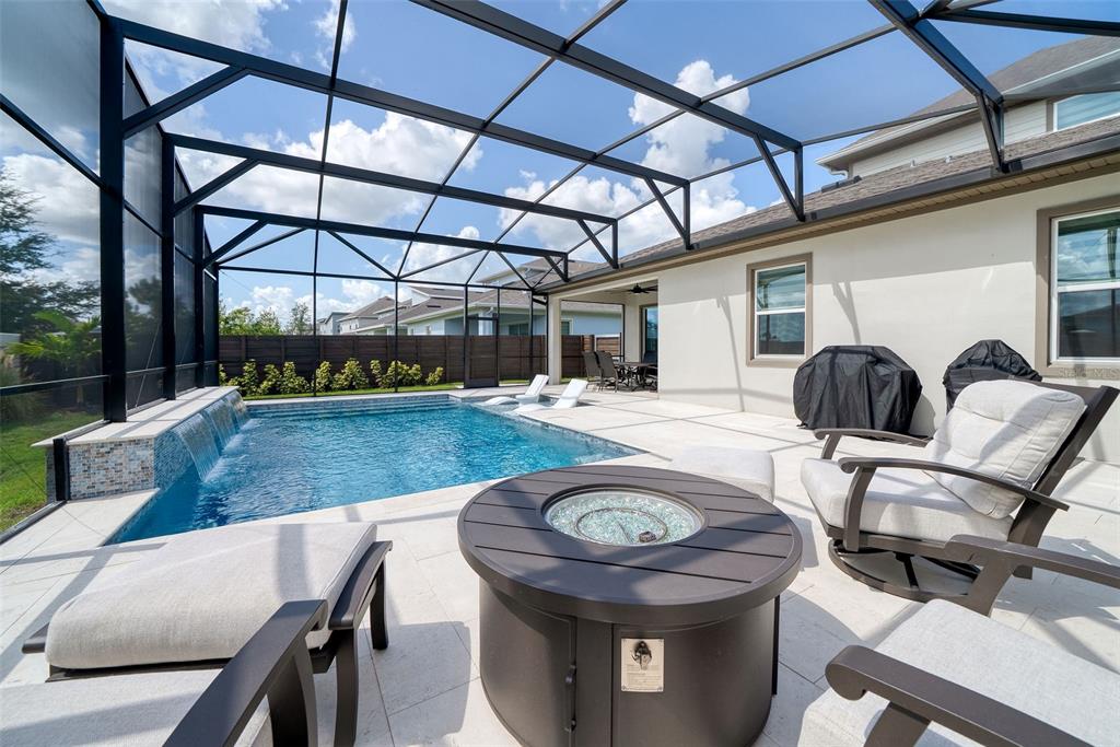 A screened-in patio features a swimming pool with a waterfall and a fire pit — 13175 MCMILLAN, ORLANDO, FL