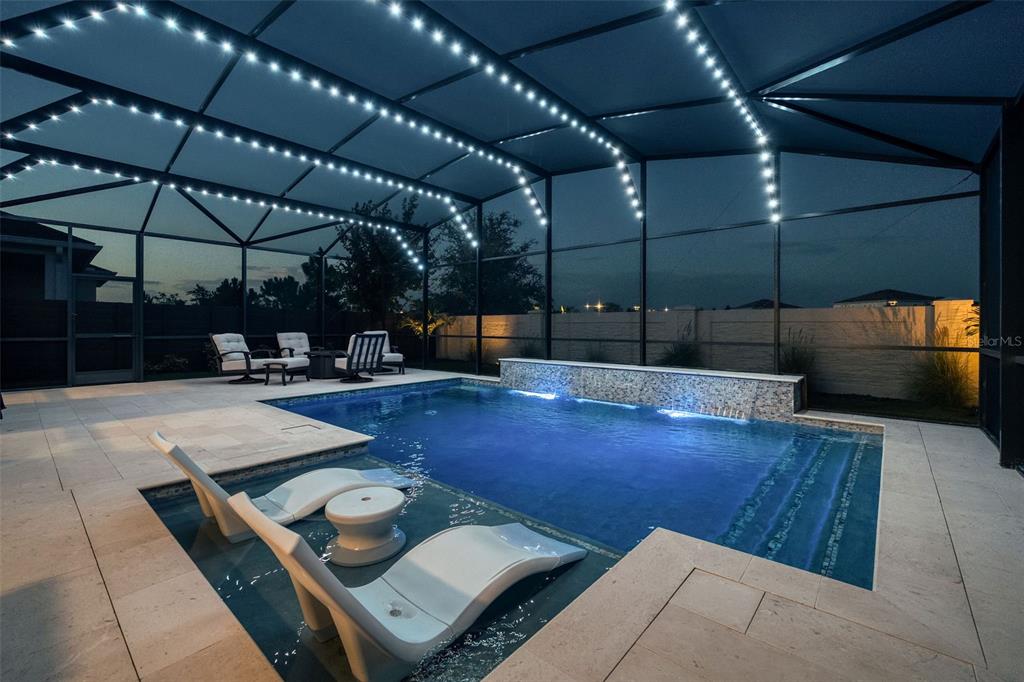 A swimming pool with lounge chairs and a water feature inside a screened-in patio — 13175 MCMILLAN, ORLANDO, FL