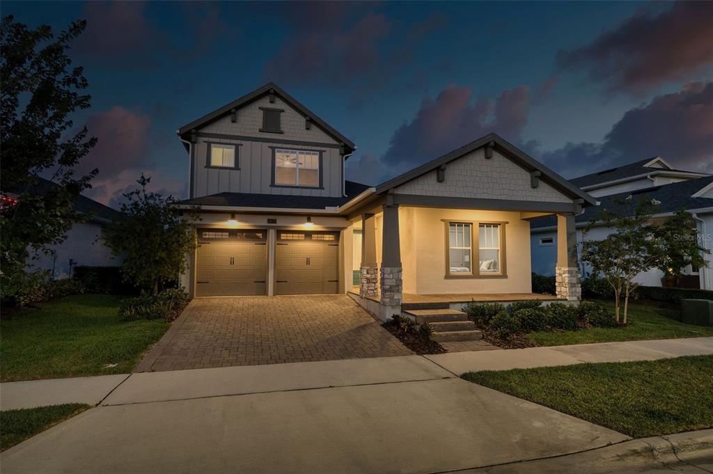A two-story house with a two-car garage and a covered front porch at dusk — 13175 MCMILLAN, ORLANDO, FL