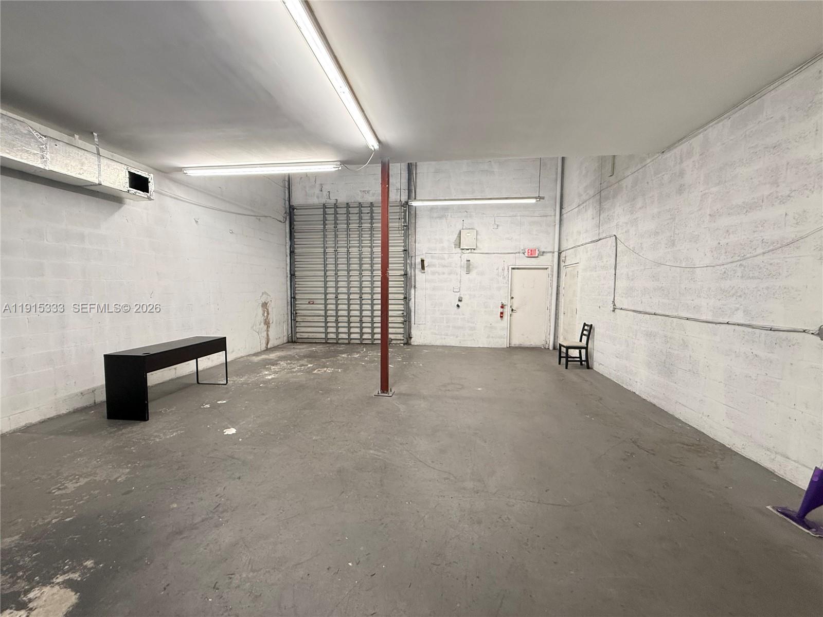 An empty industrial space features white painted block walls, a concrete floor, and a metal door — 8000 NW 31st St # 19, Doral FL 33122, DORAL, FL